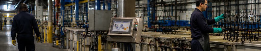 Shared process monitoring panel on a plating line while nearby operators continue other work, illustrating a visible signal without a defined response owner